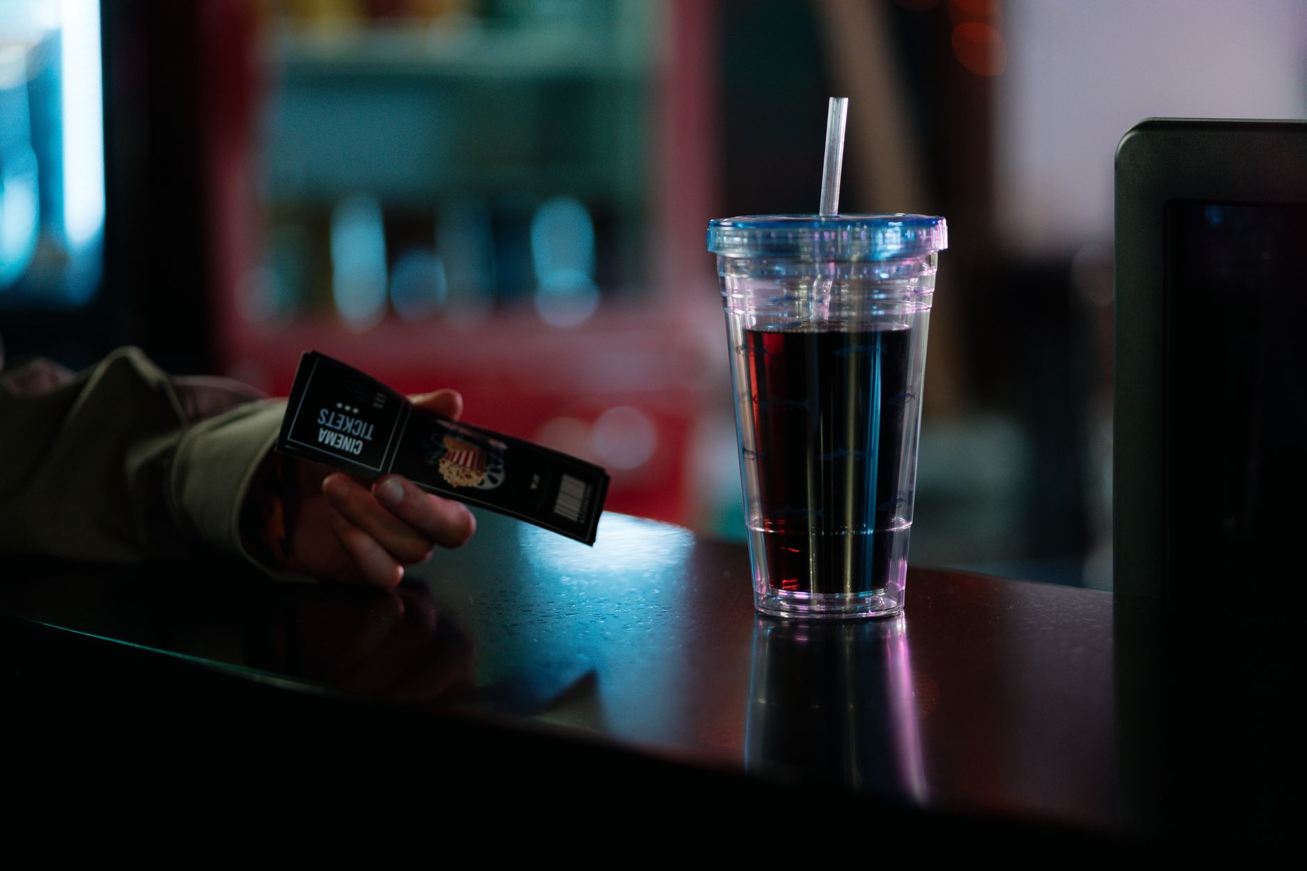Gros plan de billets de cinéma et d'une tasse de soda sur un comptoir. Idéal pour les thèmes de divertissement.